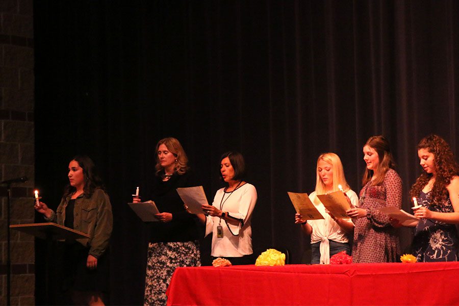 Members and club sponsors recite a pledge in Spanish during the ceremony.  