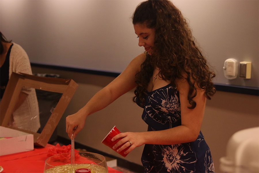 Pouring lemonade into a cup, junior Sofia Nicot serves a student waiting in line. 