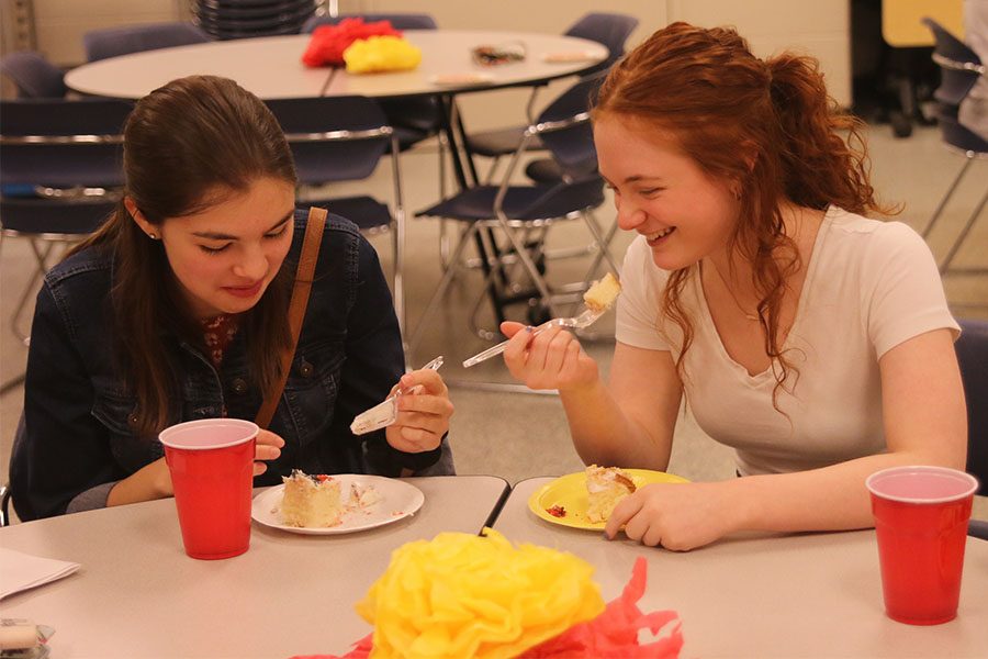 As they enjoy pieces of cake, new members Grace Emerson and Hadley Rupe laugh together. 