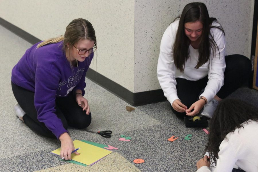 Cutting out letters, juniors Kenzie Harris and Ryleigh Reigle create their seminar door decorations.