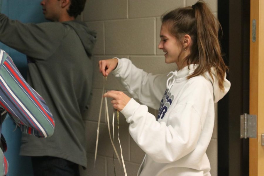 Using ribbon, sophomore Caroline Schmidt helps with decorating her seminar’s door.