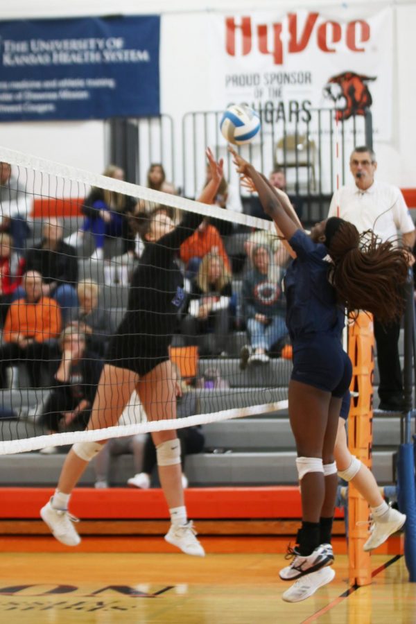 Awaiting the ball being tipped over the net, senior Faith Archibong jumps in the air and extends her arms, ready to block. 