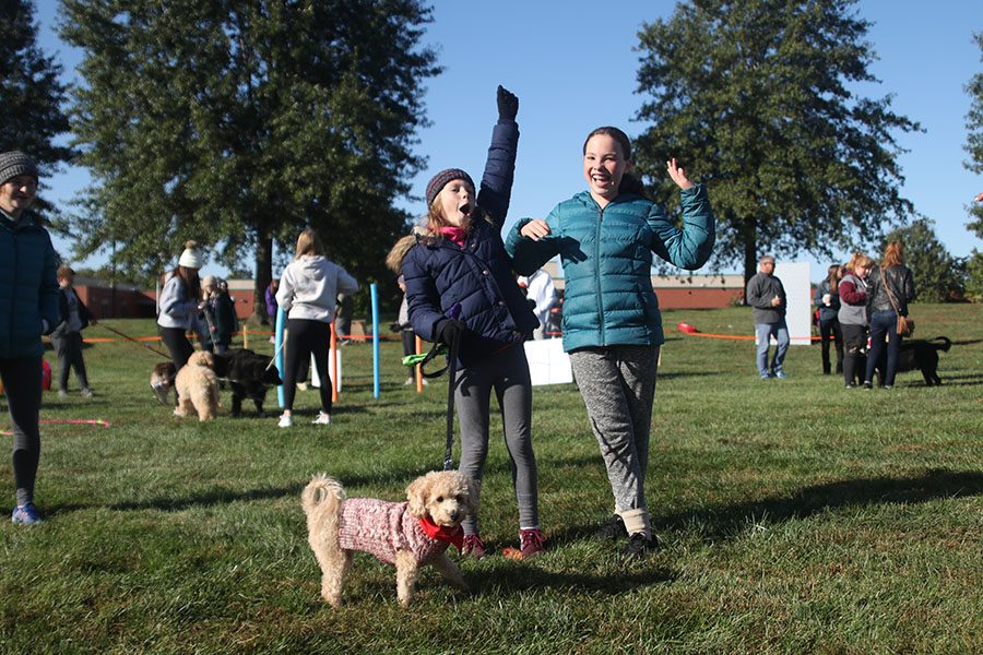 Celebrating their win of musical sits, a rendition of musical chairs for dogs, game participants throw their hands in the air.