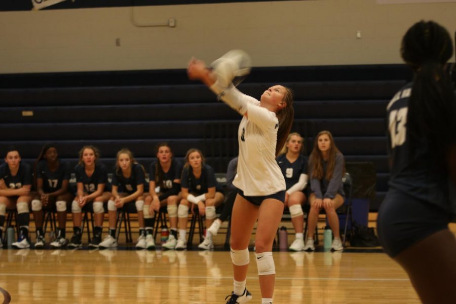 Facing away from the net, junior Jaden Ravnsborg hits the ball to her teammates.