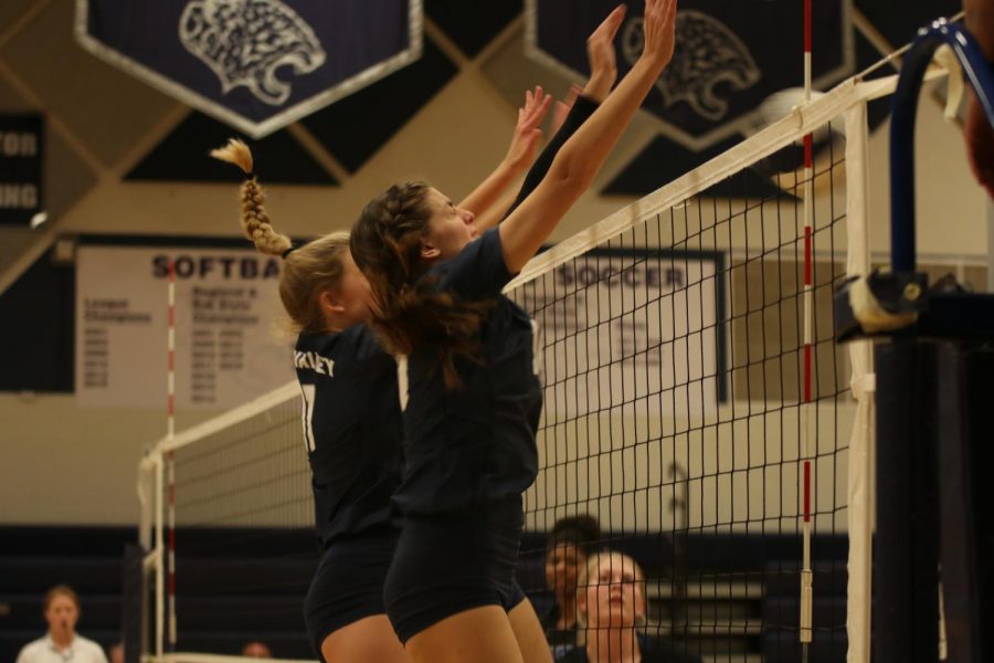 Jumping in the air, junior Molly Carr and sophomore Kate Roth prepare to block the ball.