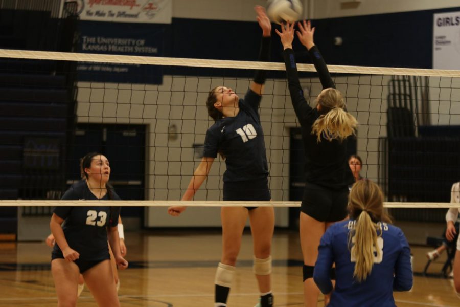 One hand raised, junior Molly Carr blocks the ball.