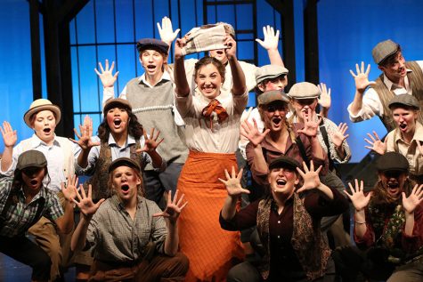 Holding a newspaper, senior Analiese Wilhauk smiles towards the audience. The cast will perform shows throughout the week of Saturday, Nov.  9 through Sunday, Nov. 17.