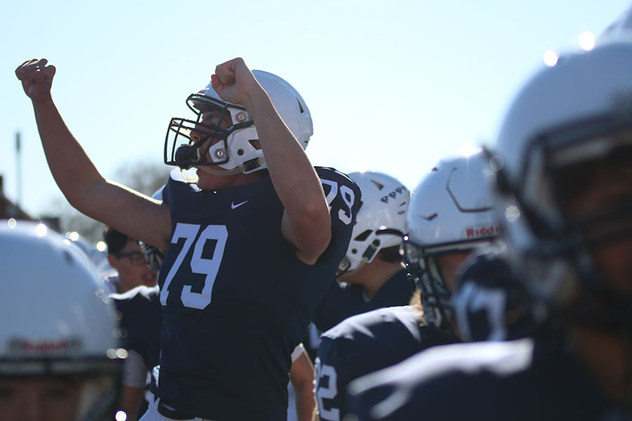 Watching the game, senior Nathan Janssen throws his hands up in celebration. 