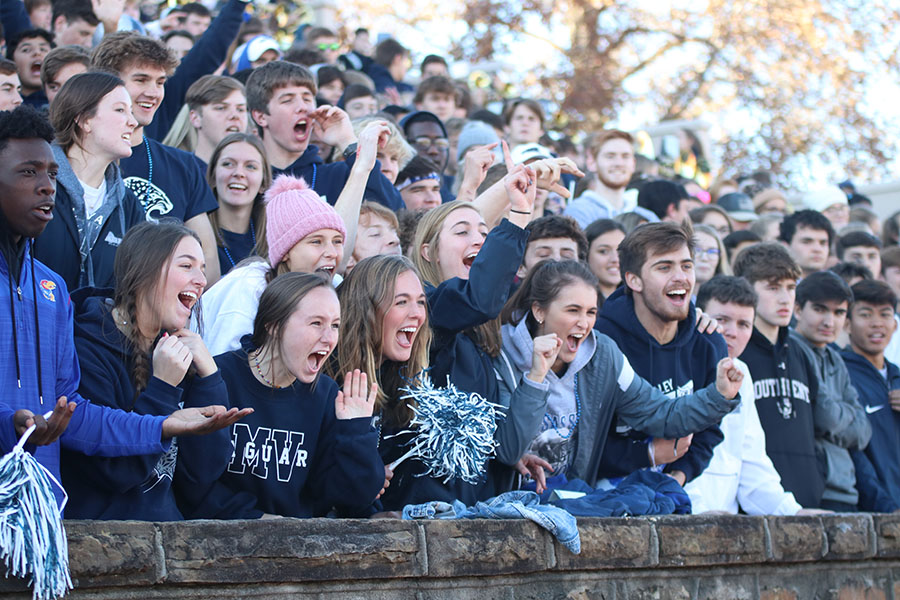 Cheering on the team, the crowd yells in support. 
