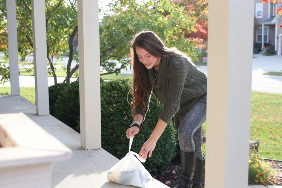 Retrieving+a+bag+of+goods+from+a+home%E2%80%99s+porch%2C+junior+Katherine+Weigel+travels+door+to+door+through+Lakepointe+neighborhood+picking+up+filled+Trick+or+Treat+So+Others+Can+Eat+bags.+StuCo+members+and+other+volunteers+delivered+empty+bags+with+instructions+to+neighborhoods+surrounding+the+school+Monday%2C+Nov.+3+and+picked+up+filled+bags+Wednesday%2C+Nov.+6.