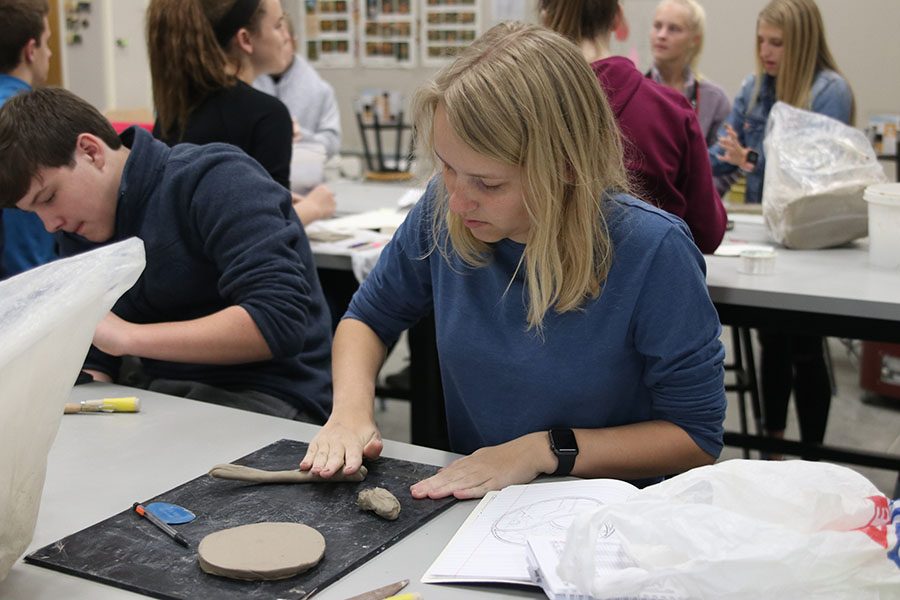 Focusing intently, senior Callie Roberts rolls a coil to enhance her one-word tile design.