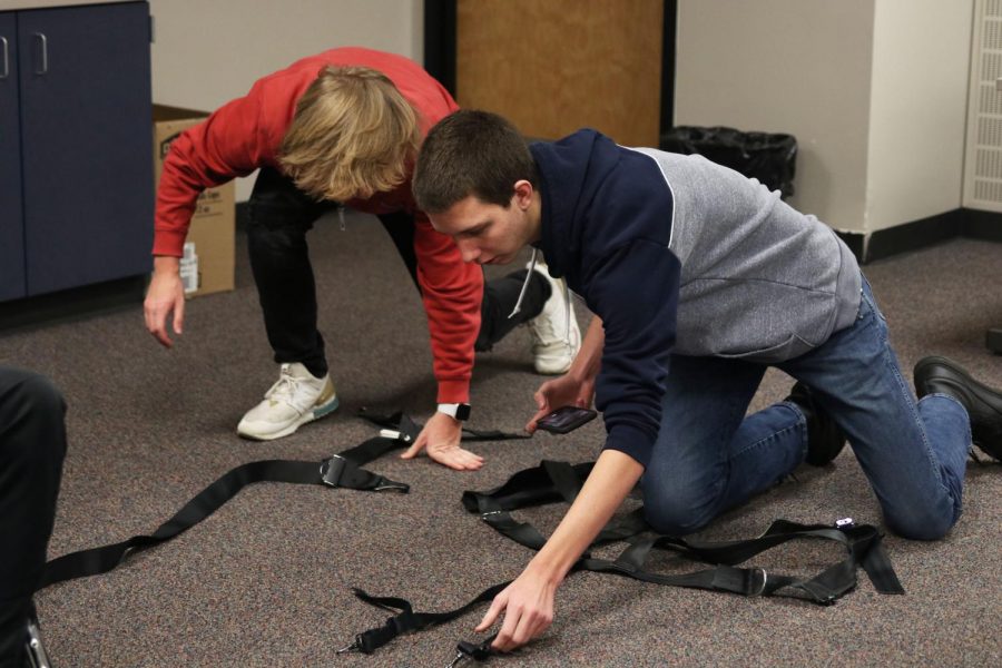 Putting the straps in place, seniors Bret Bellmyer and Alex Heinking lay out the harness on the ground.