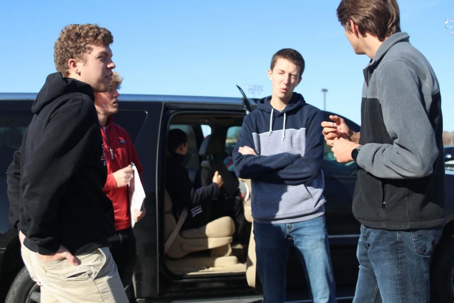 Standing next to the car, the engineering students discuss their project.