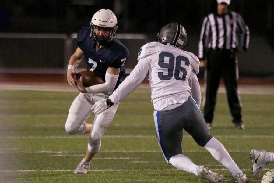 Running with the ball, junior Cooper Marsh tries to get past a defender.