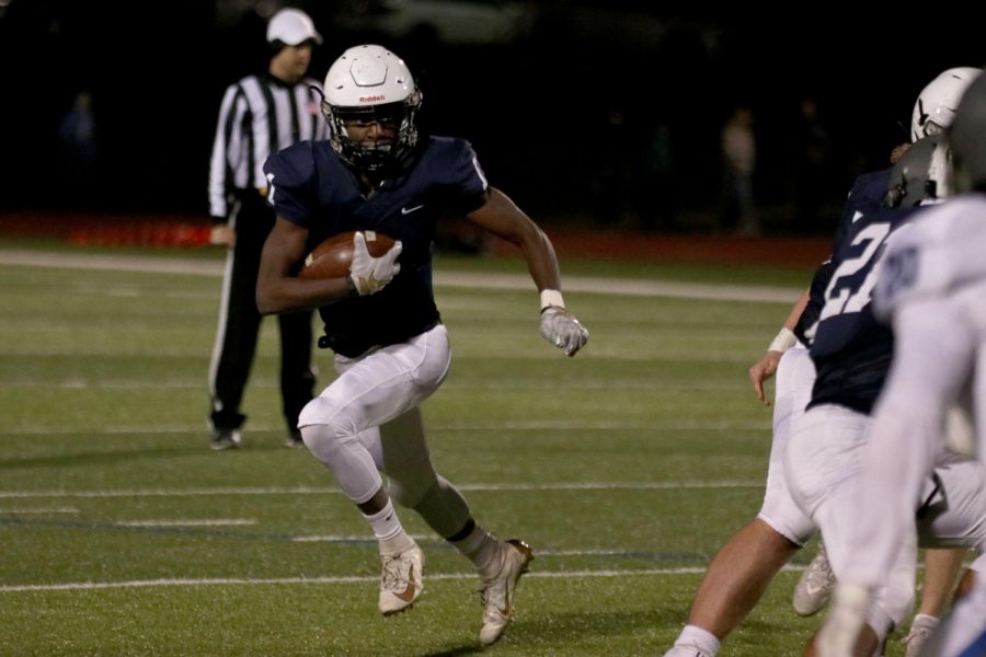 Avoiding the opposing team, junior Quin Wittenauer runs with the ball.