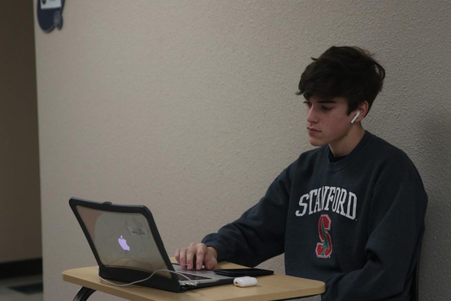 Sitting in the hallway doing his homework, junior Dutch Platt works as a hall monitor at the tournament 
