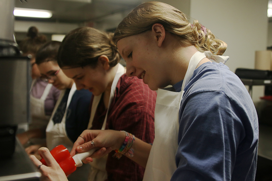 Inspecting a pepper, sophomore Isabel Aerni gently carves out the whiter parts of the pepper while volunteering for NourishKC Thursday, Nov. 21. 