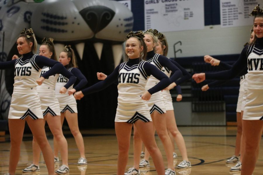 Smiling, senior Trinity Ouellette and the rest of the cheer team perform their first cheer of the pep rally Friday, Nov. 29.