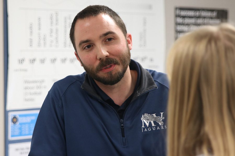 Listening intently, physics teacher Ryan Johnston speaks with a student.