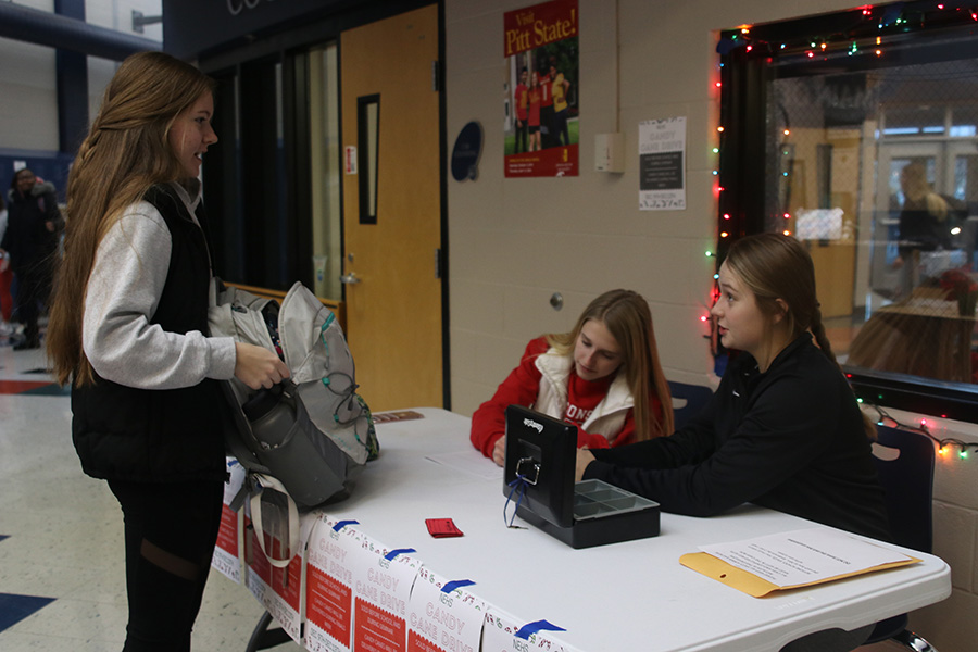 Buying a candy cane from sophomore Bridget Roy and junior Callie Shryock, junior Emily Feuerborn supports NEHS in their annual candy cane sale the week before finals.
