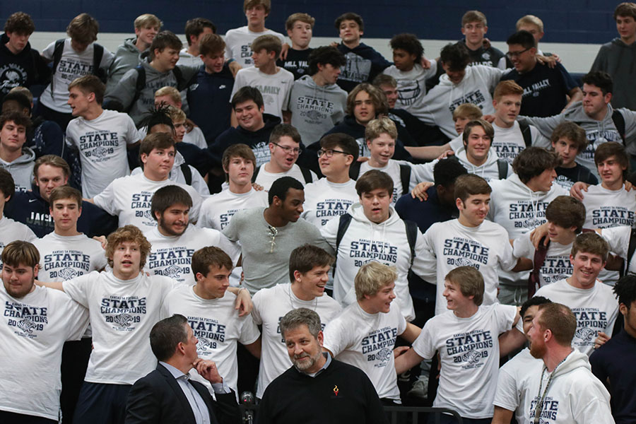 Swaying back and forth, the state champion football team stands with arms around one another to conclude the pep assembly Thursday, Dec. 12. 