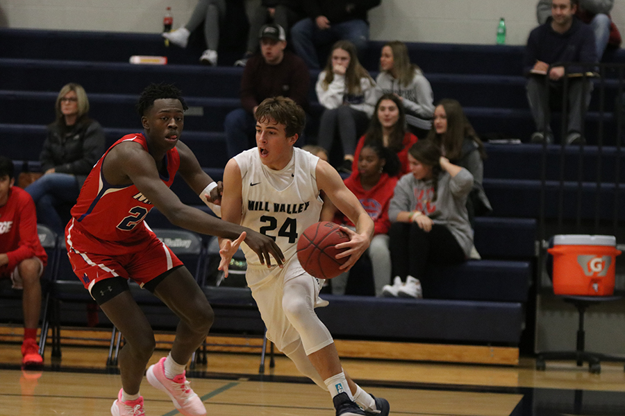 Senior Jack McGuire cuts through defenders, dribbling across the court to find a place to shoot. The team fell to Bishop Miege 55-54 in the schools Winter Homecoming game Friday, Jan 10.