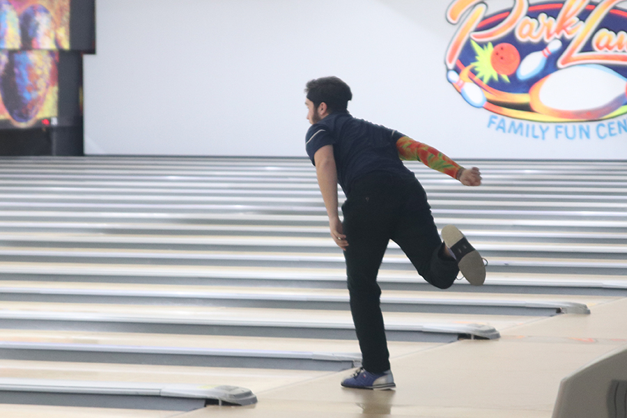 Standing on one foot, junior Simon Hall watches his ball hit the pins.