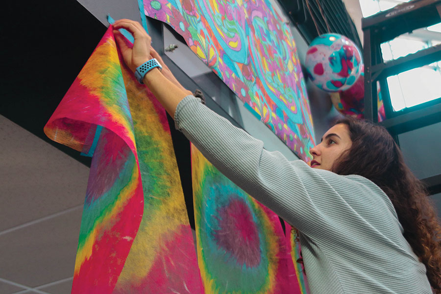 Hanging tie-dye banners in the main entrance, junior Nicole Crist attends StuCos spirit week decorating on Sunday, Jan. 5.