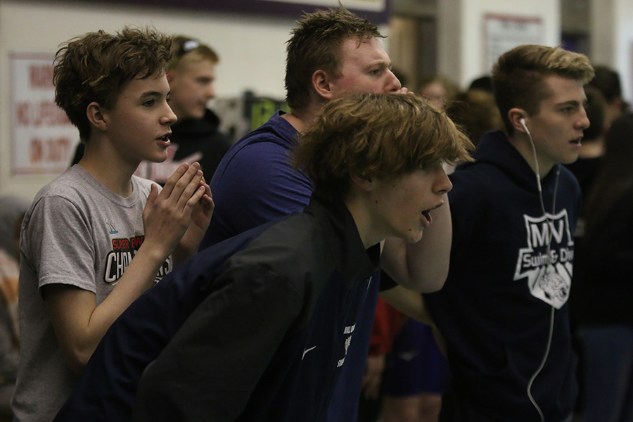 Cheering on their teammate, a few of the swimmers gather at the end of their teammates lane.