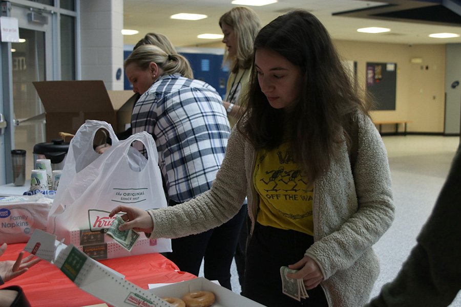 Giving money, sophomore Natalia Hernandez buys a donut.
