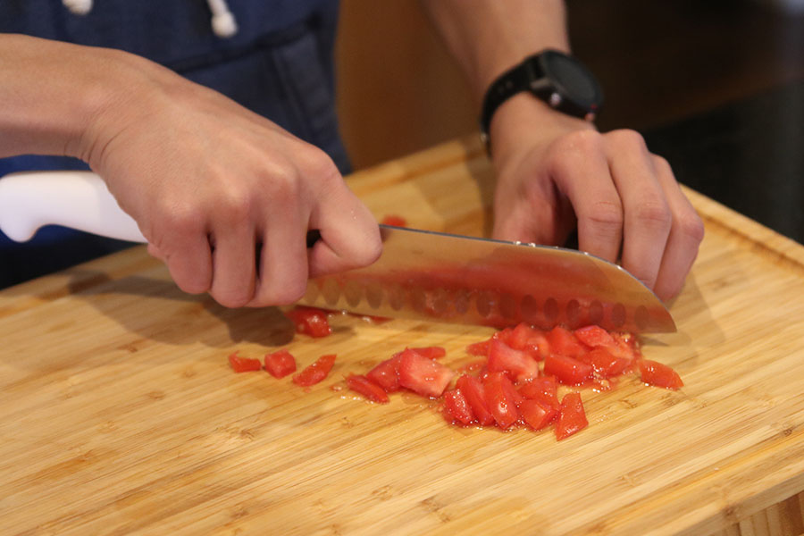 After browning the meat, senior Nico Gatapia dices a tomato to add to the dish later.
