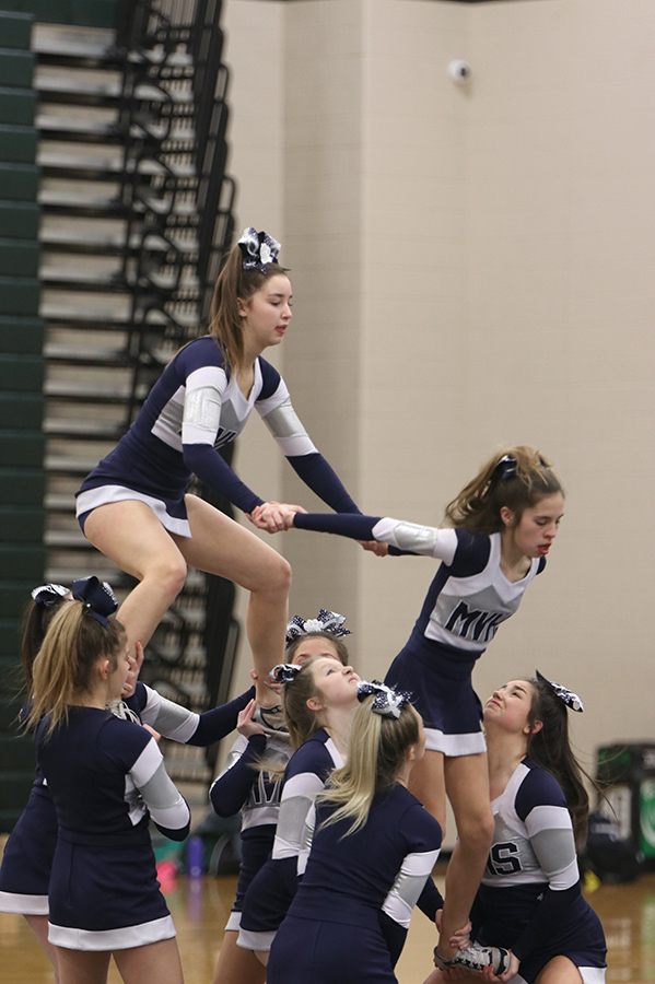 In the middle of a stunt, junior Claire Dinslage pulls up teammate freshman Sidney Claeys. 