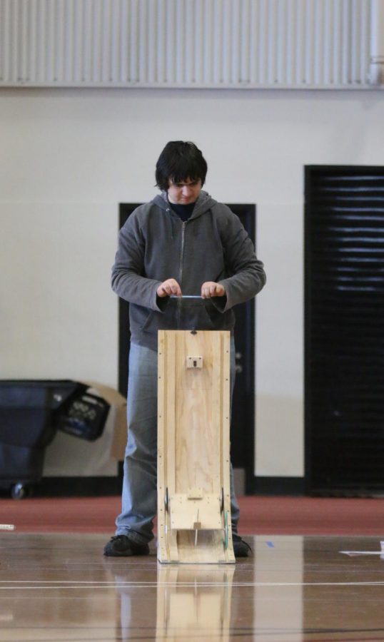 After setting up the vehicle ramp for the event Gravity Vehicle, junior Andrew Gawith uses a pencil to release the vehicle from its initial vertical position at the top. Gravity Vehicle is an event where a team of up to two attempts to build a ramp and vehicle to reach a designated location; the closer the vehicle can make it to the marked point, the better. Gawith and his partner, sophomore Jordan Manning, placed fifth overall.
