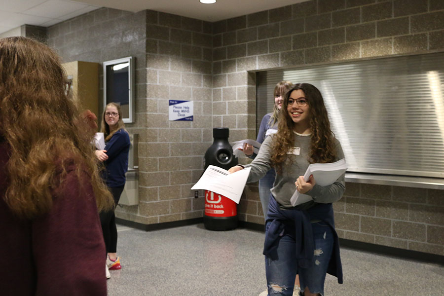 Welcoming people inside, junior Sofia Nicot greets the incoming freshmen and gives them an information pamphlet. 