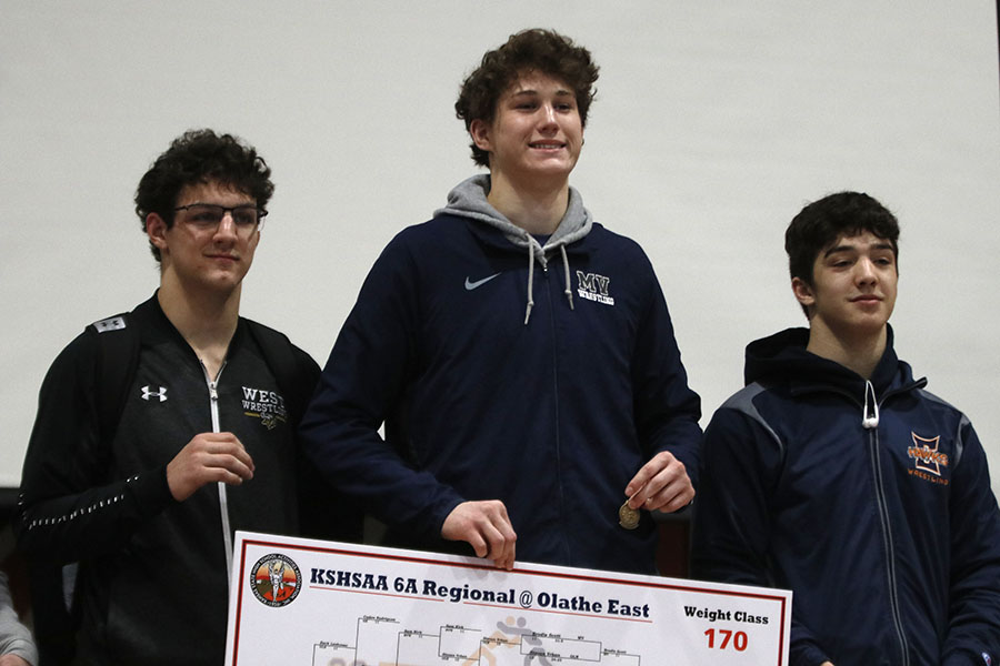 Accepting first place in the 170-pound weight class, junior Brodie Scott stands on the podium.