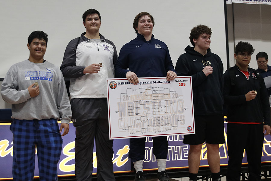Standing on the podium, junior Ethan Kremer is awarded first place in the 285-pound weight class.
