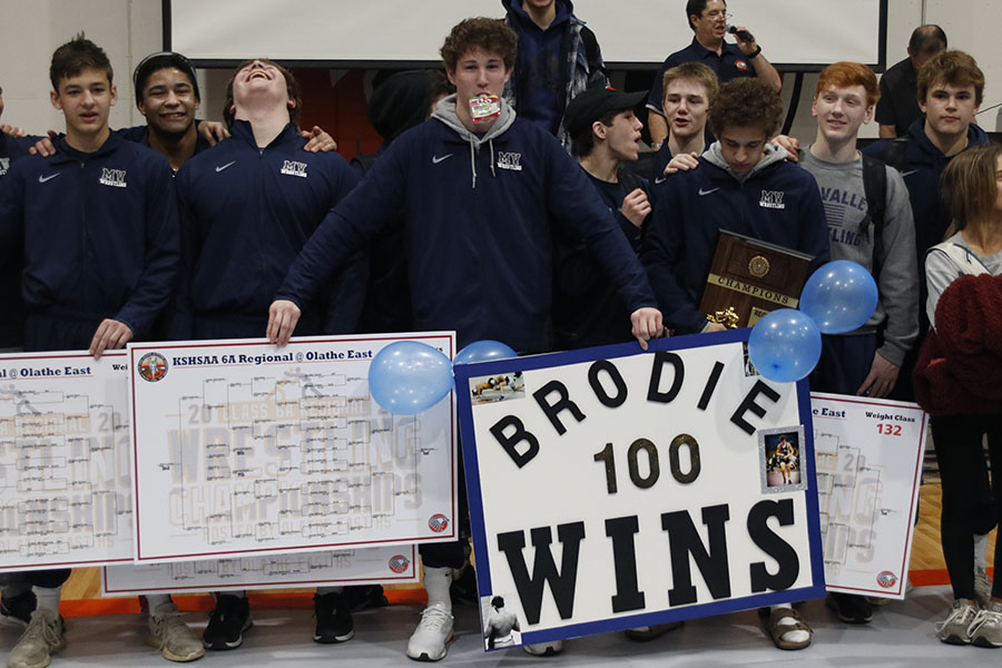 Standing with his teammates, junior Brodie Scott celebrates his 100th victory.