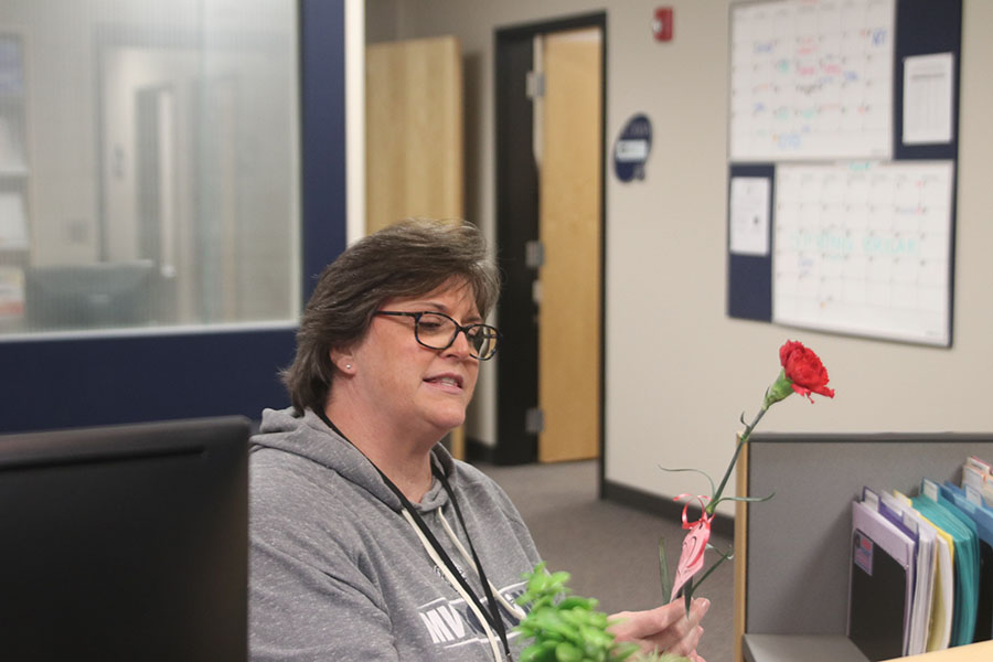 Looking at her carnation, counseling secretary Judith Intfen reads who it is from. 