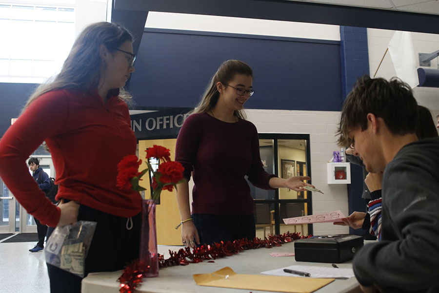 Handing the English NHS members money, senior Joan Downey and sophomore Allision Rader buy carnations Thursday Feb. 7. 