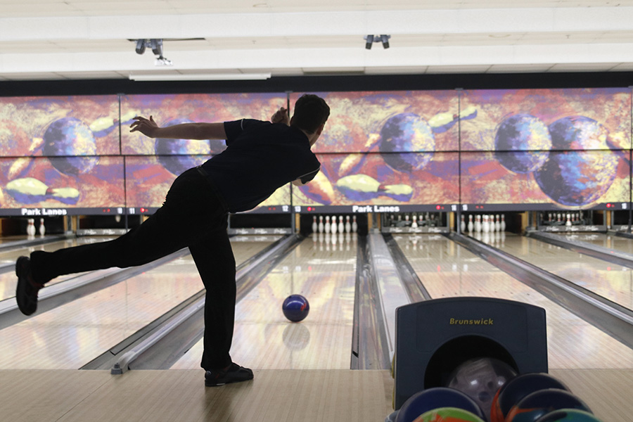 Standing on one foot, junior Jackson Penny watches as his ball rolls down the lane.