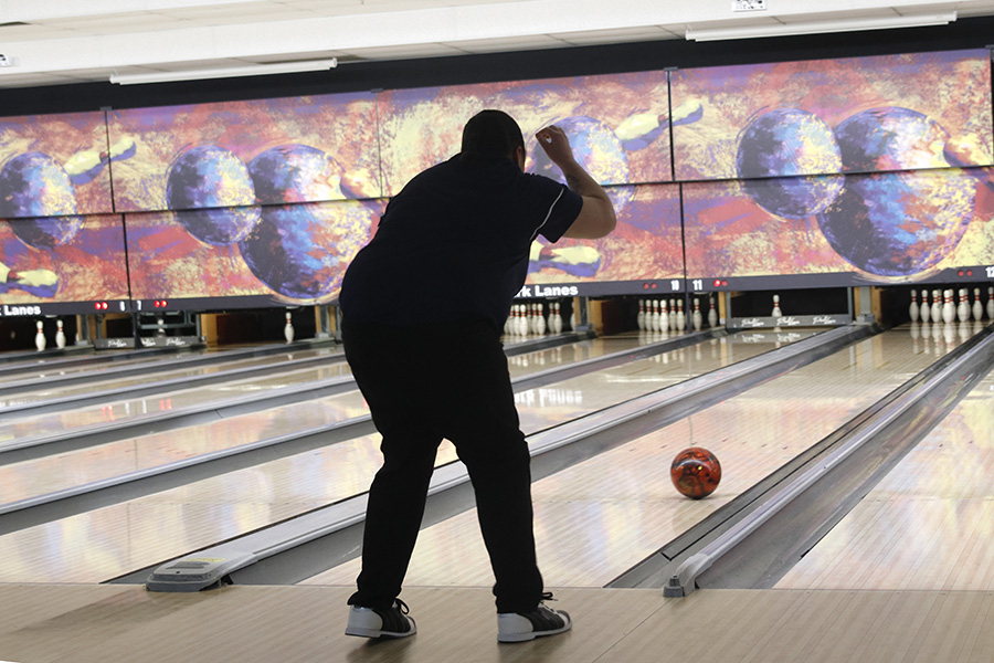 Arm in the air, senior Brianna Davis watches her ball roll toward the pins.