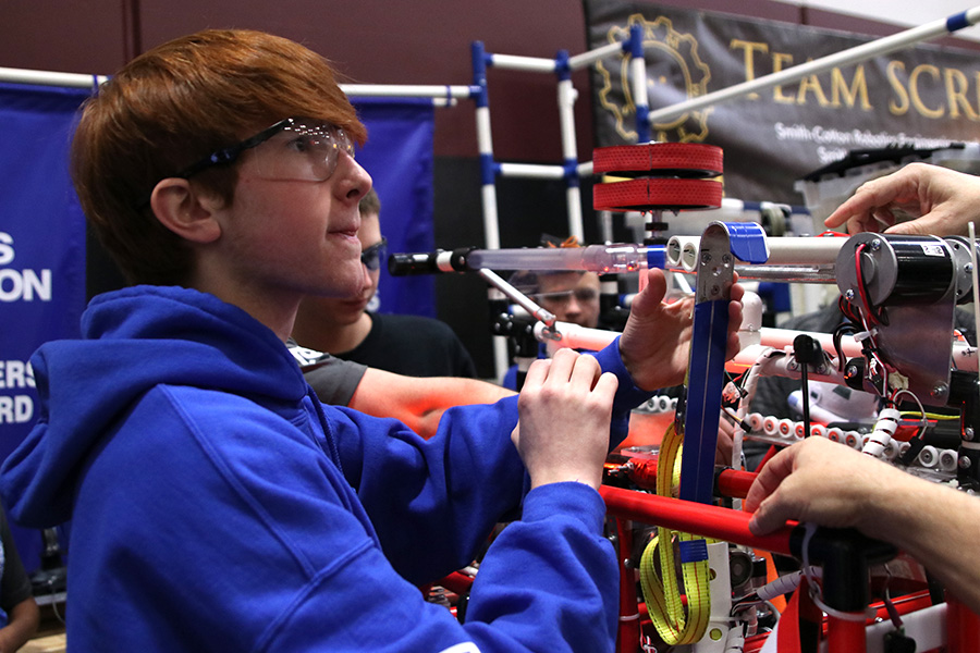 Evaluating the damage from the last match, sophomore Darren Hall helps fix the robot in the pit. 