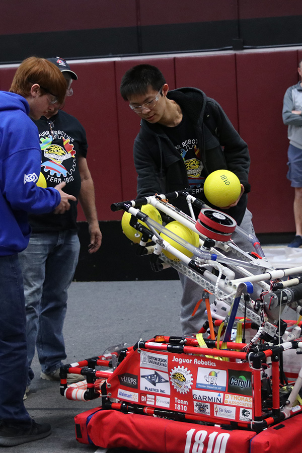 On the practice field, senior Kevin Lee loads the robot with the neon dodgeballs required for the game, also referred to as “power cells.”