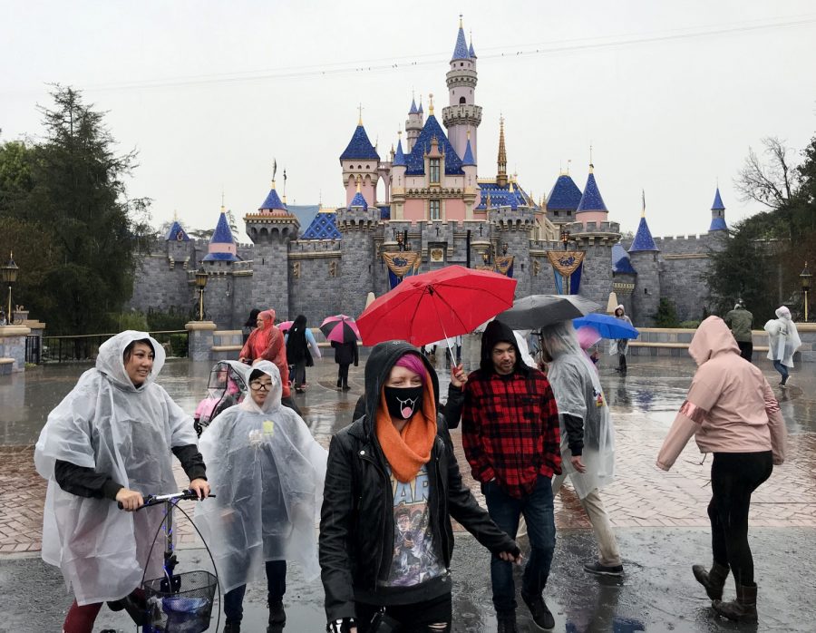 A guest wears a face mask in front of the Sleeping Beauty Castle while visiting Disneyland amid rain showers in Anaheim, Calif., on March 12, 2020. Disneyland will temporary close the Disneyland Resort in Anaheim in response to the expanding threat posed by the Coronavirus Pandemic. The closure takes effect Saturday and lasts through the end of March. Disneyland and Disney California Adventure will close Saturday morning through the end of the month in response to Gov. Gavin Newsom and state health officials' recommendation that gatherings of 250 or more people be canceled across the state, company officials said. 