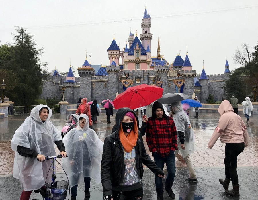 A guest wears a face mask in front of the Sleeping Beauty Castle while visiting Disneyland amid rain showers in Anaheim, Calif., on March 12, 2020. Disneyland will temporary close the Disneyland Resort in Anaheim in response to the expanding threat posed by the Coronavirus Pandemic. The closure takes effect Saturday and lasts through the end of March. Disneyland and Disney California Adventure will close Saturday morning through the end of the month in response to Gov. Gavin Newsom and state health officials recommendation that gatherings of 250 or more people be canceled across the state, company officials said. 