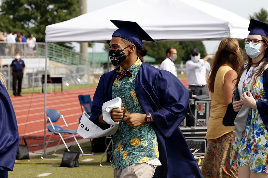 Holding her diploma, senior Paige Oliver smiles before sitting back down in her seat.
