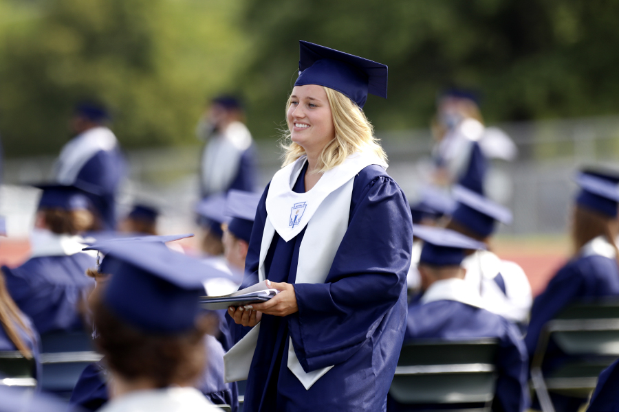 Holding her diploma, senior Paige Oliver smiles before sitting back down in her seat.
