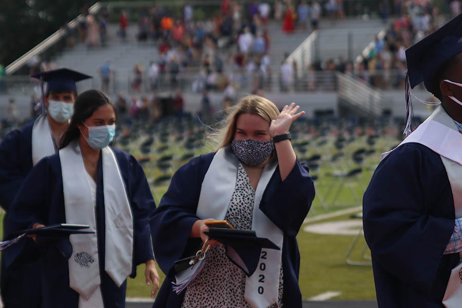 Proceeding the ceremony, senior Cadee Morris waves at her family in the stands.