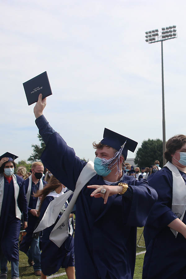 Looking at his supporters in the stands, senior Jackson King waves his diploma in the air. 