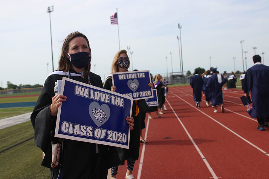 While students make their way out of the field where the ceremony itself was held, teachers such as art teacher Erica Crist, held up congratulatory signs.